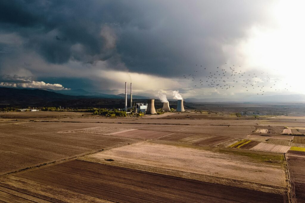 Aerial view of empty fields near atomic power station generating energy and polluting atmosphere by Petar Avramoski