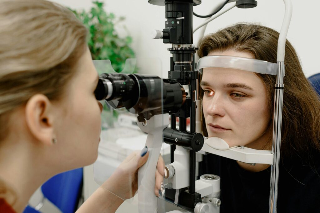 Concentrated female medical specialist using professional tool for checking vision of patient in contemporary ophthalmology clinic by Ksenia Chernaya