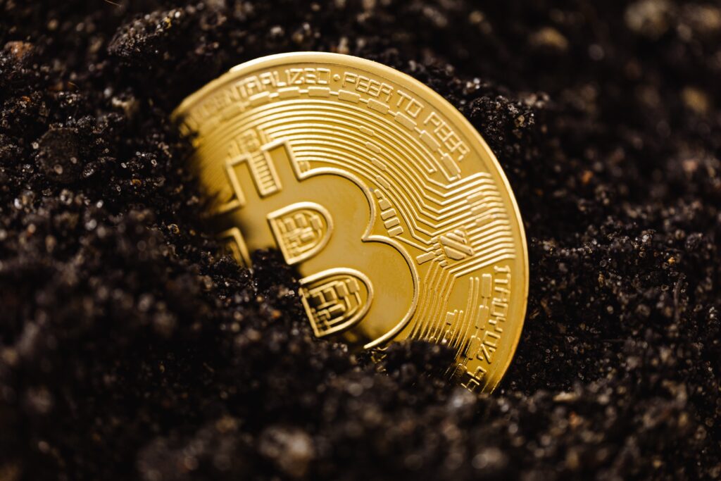 Close-up of a Bitcoin Coin Lying in Dirt on the Ground  by Karolina Grabowska