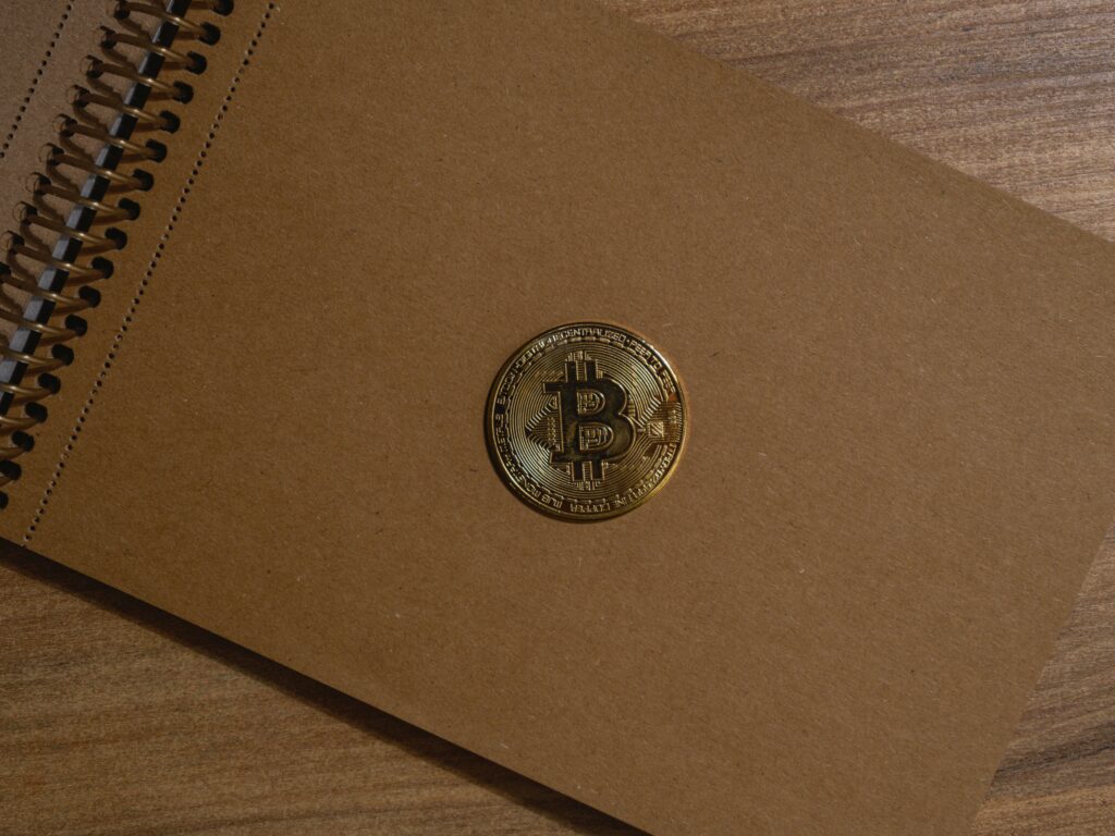 Close-up Photo of Gold Bitcoin on a Notebook  by Engin Akyurt