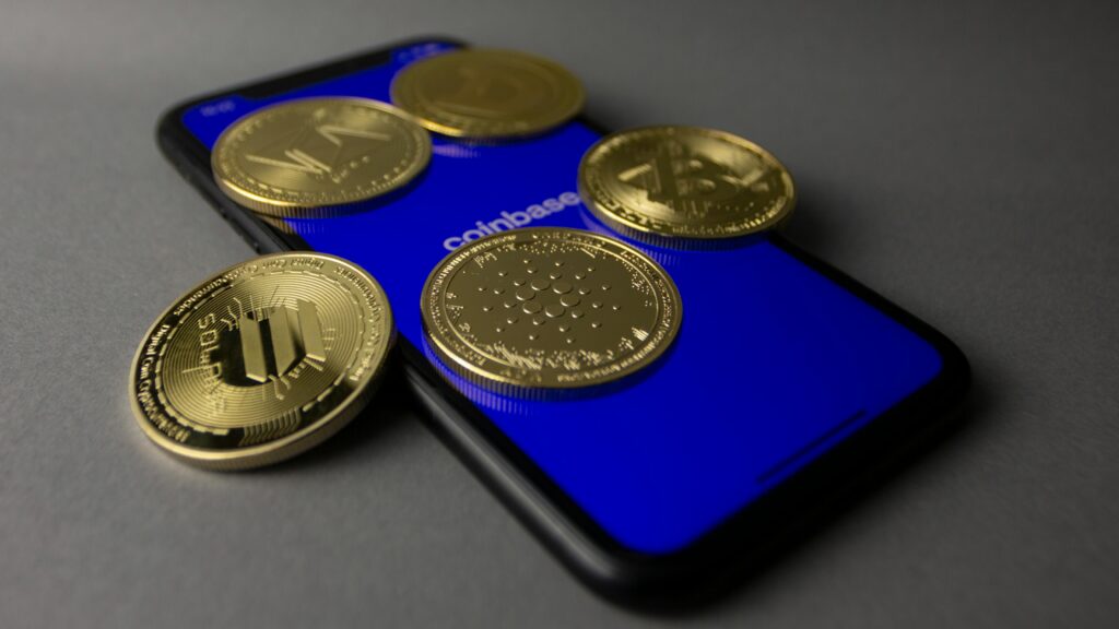 Studio Shot of Gold Bitcoins Lying on Top of a Smart Phone by Bastian Riccardi